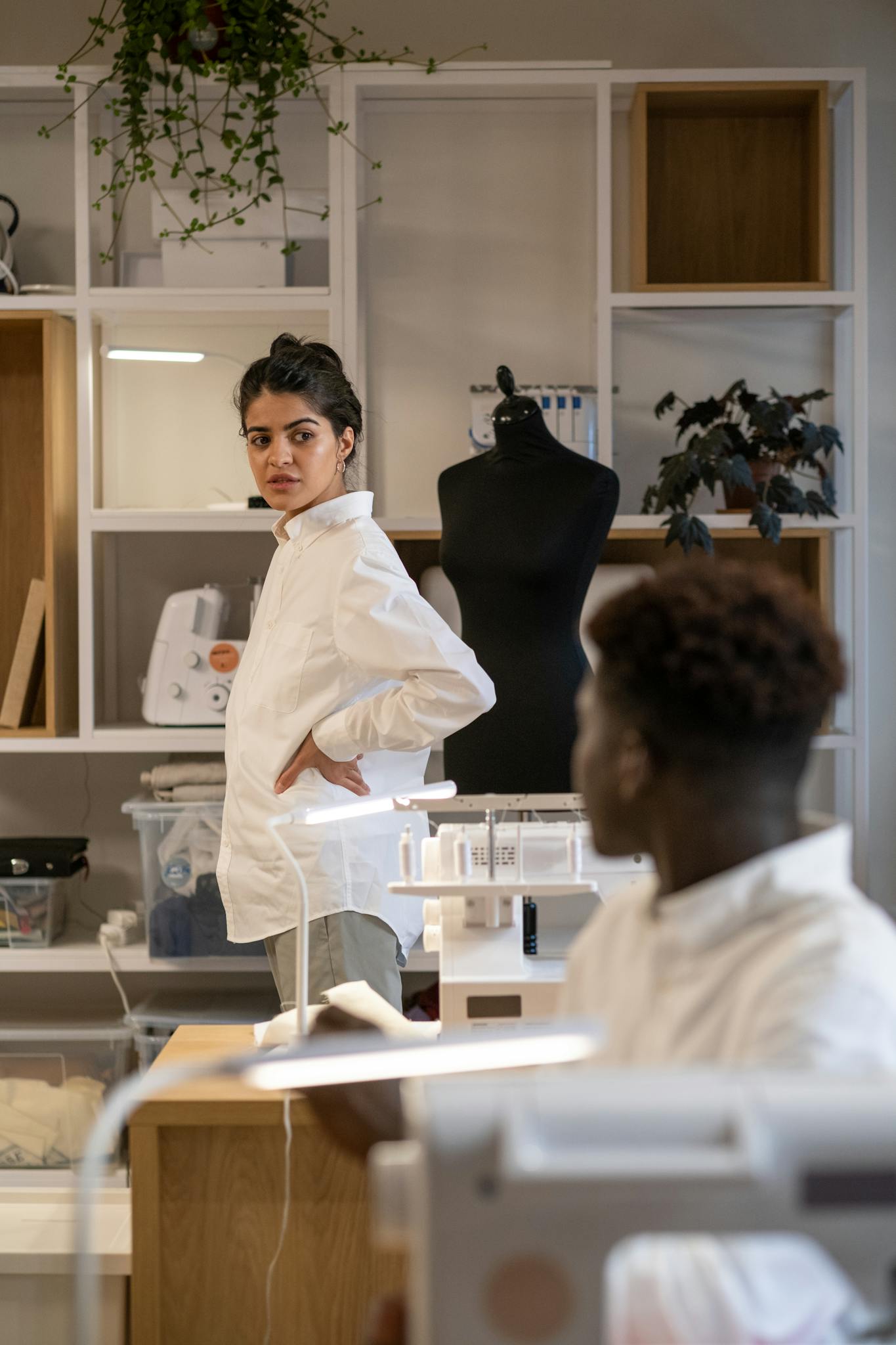 Creative fashion designers working in a modern sewing workshop with mannequins.