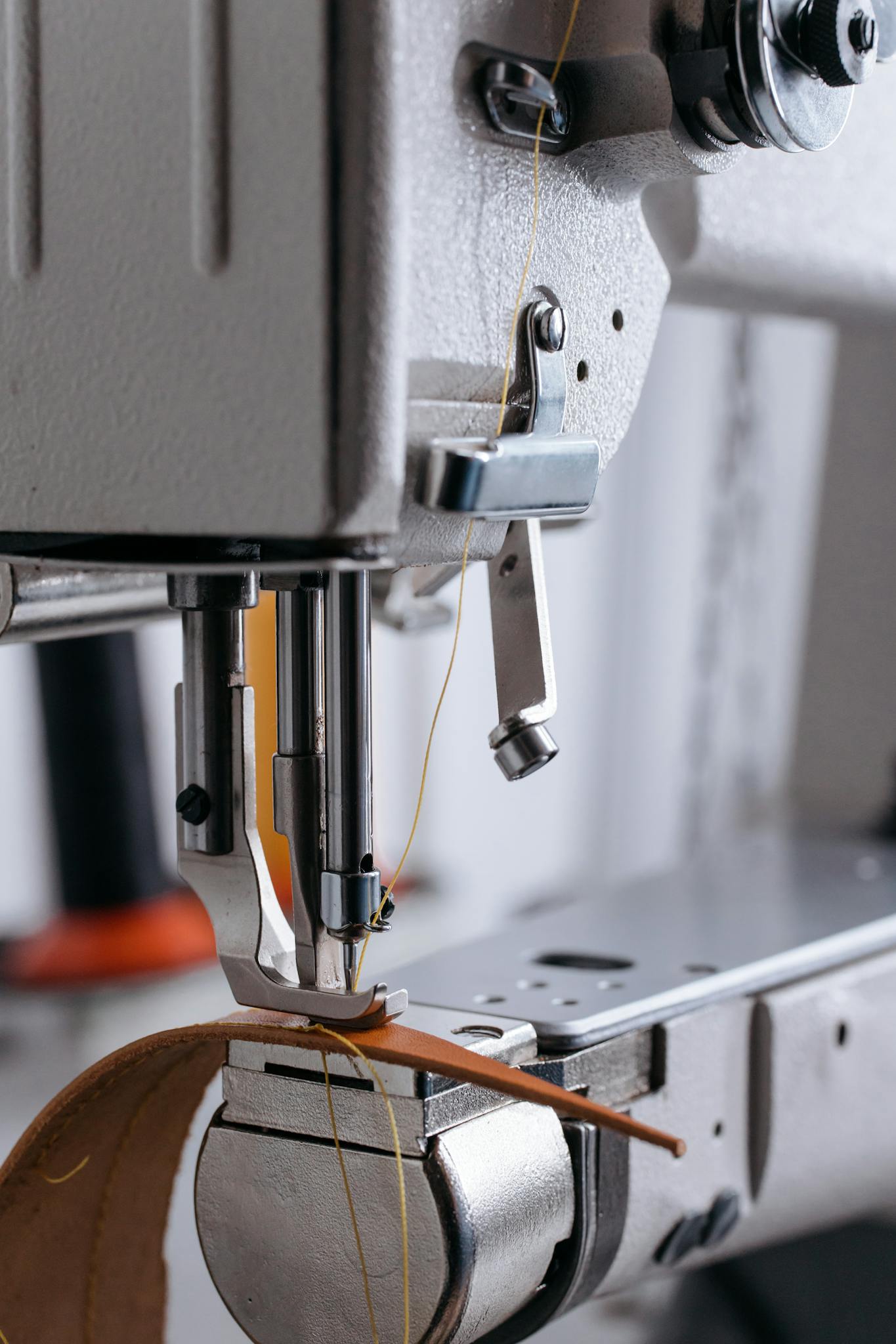 Detailed shot of a sewing machine stitching leather, showcasing precision work.