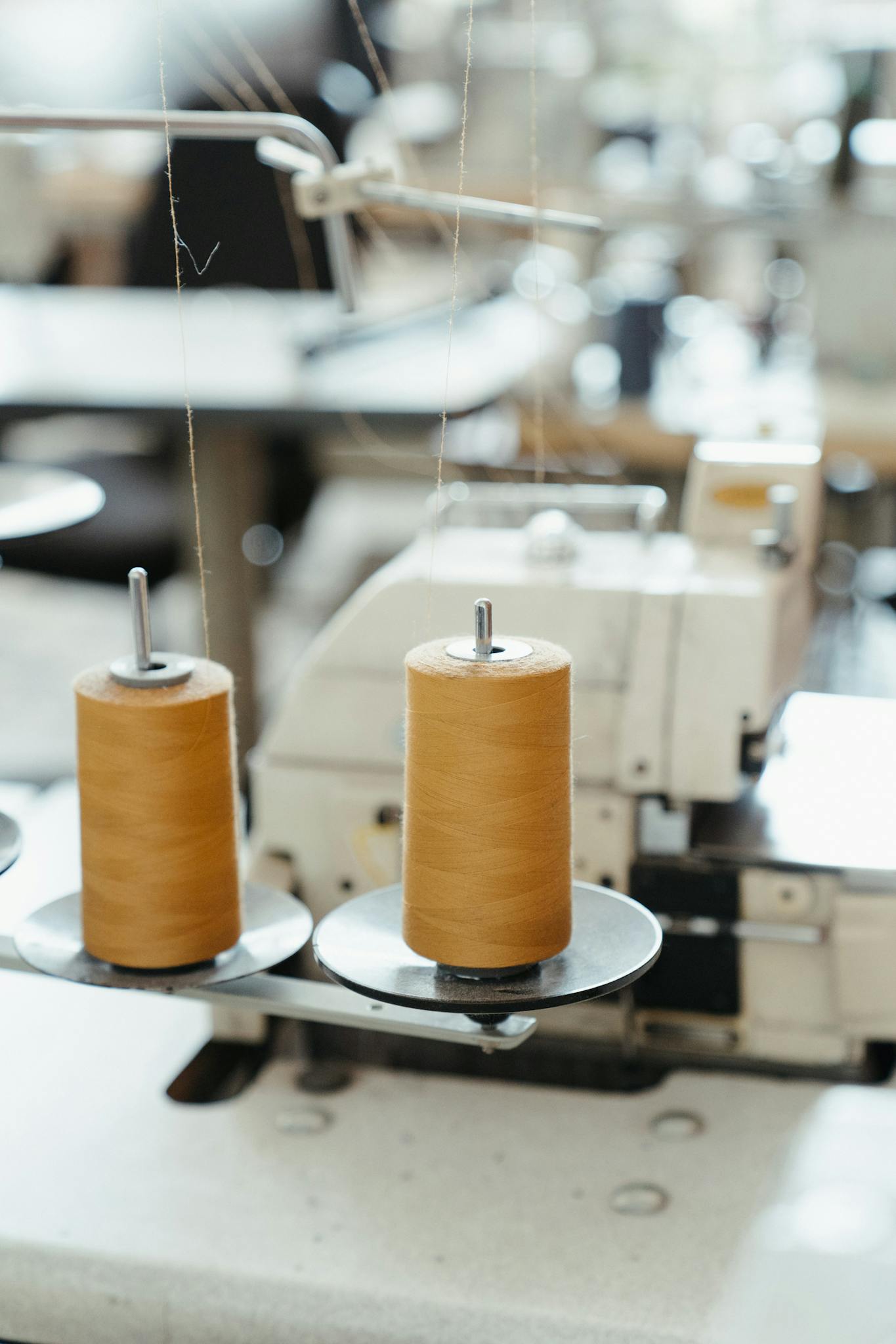 Detailed view of a sewing machine with spools of thread in a workshop setting.